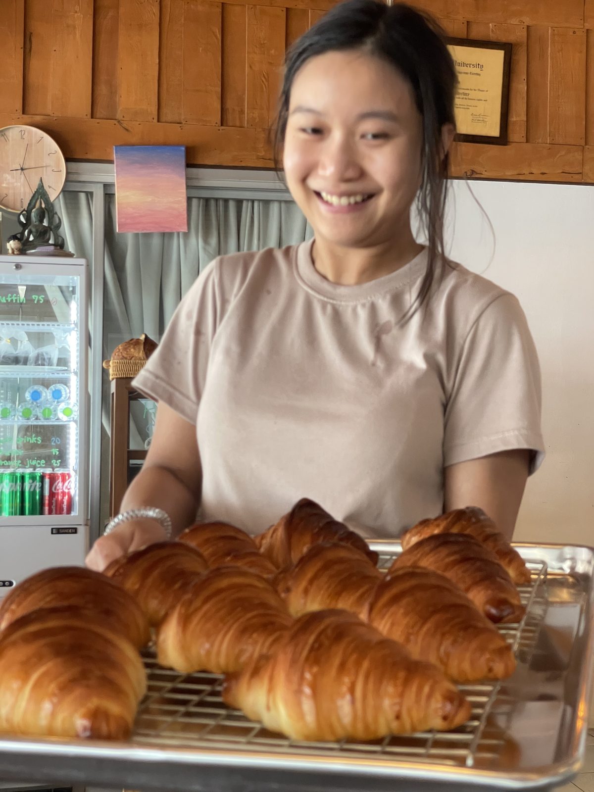 Psy holding a tray of fresh-baked croissants at Stay Cafe on Mae Ram Phueng beach.